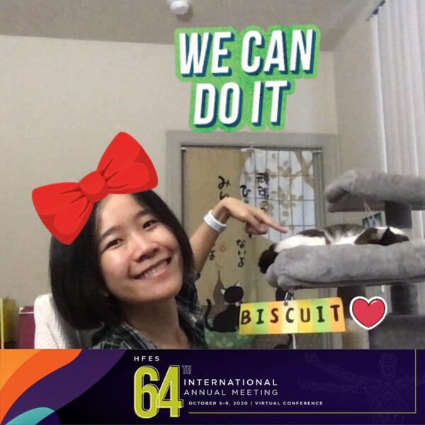 A photo of Yingchen and Biscuit, taken at the virtual photo booth of the 64th Annual Meeting of the Human Factors and Ergonomics Society. Biscuit is sleeping on his cat tree above his name tag, and Yingchen is pointing at him. The banner of the conference appears on the bottom of the photo. There is a “We can do it” sticker on the top of the photo, a red hair bow sticker on the top of Yingchen’s head, and a heart sticker next to Biscuit’s name tag.